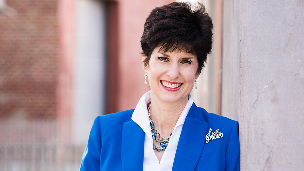 woman with short black hair, blue blazer over white shirt