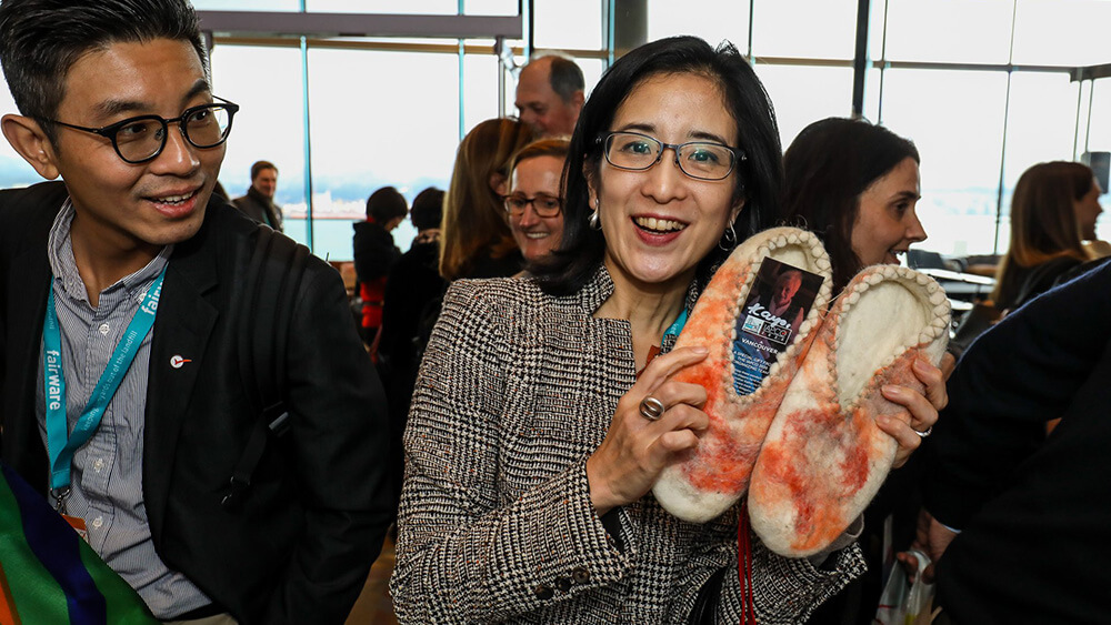 smiling woman holding woven slippers