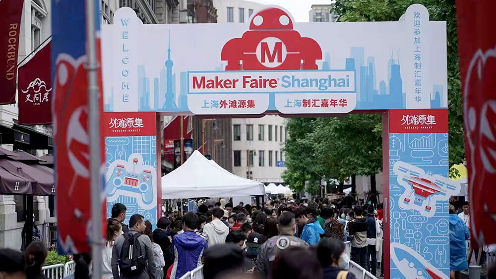 maker faire shanghai sign above people at event