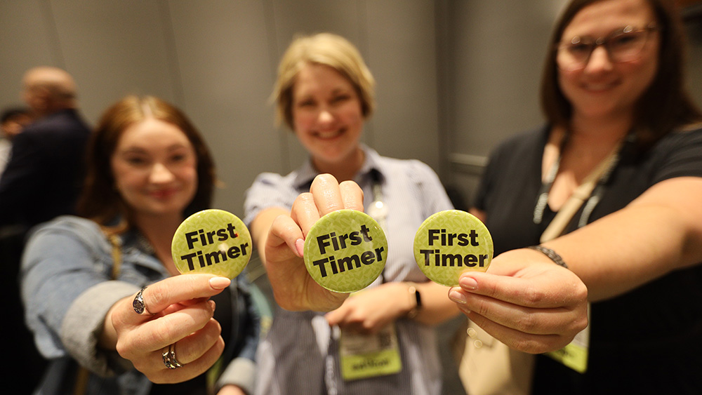 3 women hold First Timer buttons