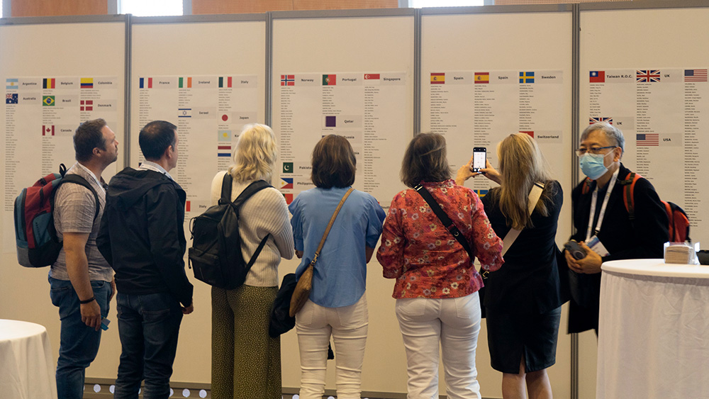 people looking at wall of posters with name and country lists