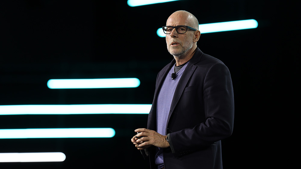 bald man with glasses in front of black background with horizontal lighting