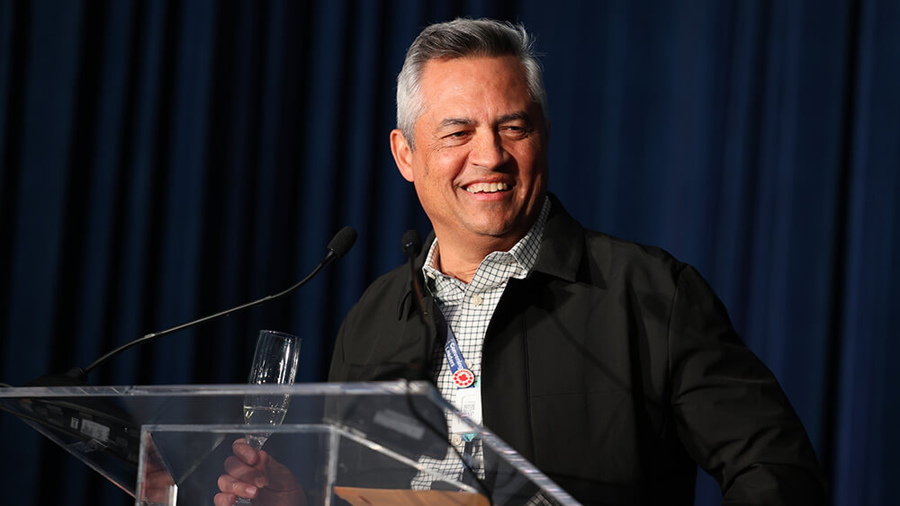 latino main with graying hair smiling behind podium